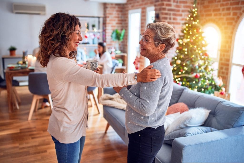 Family and friends dining at home celebrating the holidays with traditional food and decoration, women talking together happy and casual