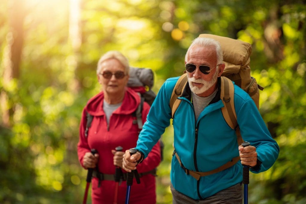 Happy senior couple walking together in a forest talking about their purpose trust.